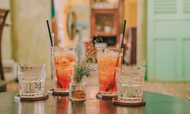 a couple of pink drinks and glasses of water on a table